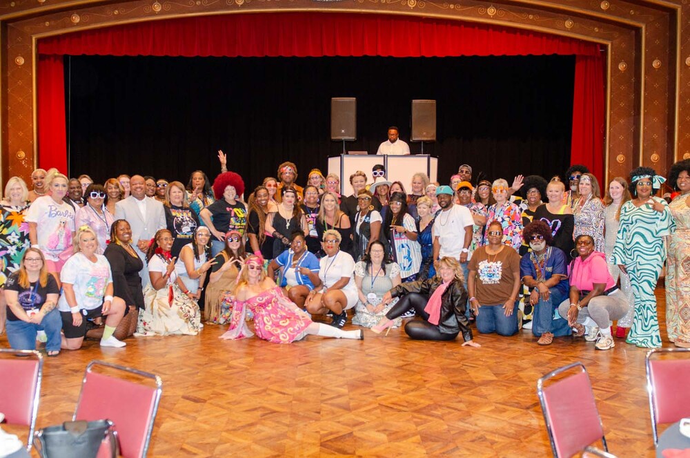 A big group photo with individuals in various decades costumes.