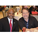 Two men smiling at the camera while sitting at a table