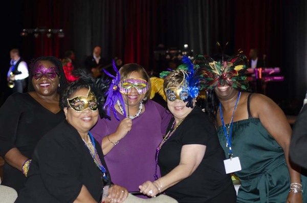 Four women wearing masks and smiling next to each other