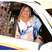 A woman sitting in a race car while smiling.