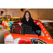 A woman standing next to a race car smiling.