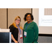 Two women standing in front of a projector screen.