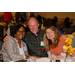 A man wrapping his arms around two women at a table.