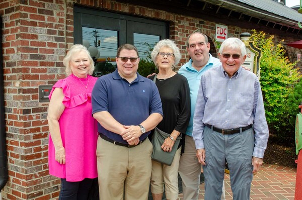 Five individuals posing for a photo outside.