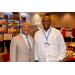 President Anthony Goodson Jr. posing with another gentleman with several booth displays int he background.