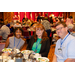 A man and two women smiling big for the camera while enjoying dinner.