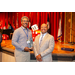 A man posing with his glass award with President Anthony.