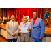 President Anthony posing with two individuals. The man in the middle is displaying his award.