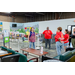 A group of individuals listening to a speaker while surrounded by clothes racks and shopping carts.