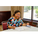 A woman sitting at a table filling out paperwork while smiling.