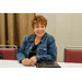 A woman sitting at a table smiling big for the camera.