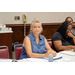 A woman listening to an individual speaking out of frame while a woman next to her points and follows along on a document.