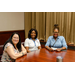 Three women sitting at the end of the table posing for a group photo.