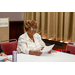 A woman holding a sheet of paper in front of herself while looking at someone across from her speaking.