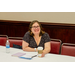 A woman with glasses and a hot Starbucks coffee smiling at the camera.