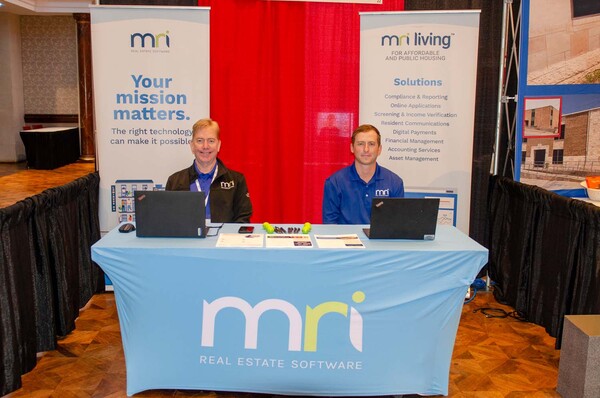 Two men sitting at their MRI Real Estate Software booth.