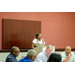 A woman speaking at the podium to the room.