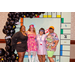 Four individuals in various decades costumes posing with the Housingopoly game board back drop.