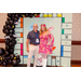 A man and a woman in 70s fashion posing with the Housingopoly game board backdrop.