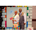 A man and woman standing back to chest inside the Housingopoly game board photo booth.