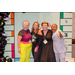 President Anthony Goodson, Jr. posing excitedly with two women in 80s fashion and a woman in 50s fashion inside the Housingopoly game board photo booth.