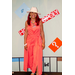 A woman in a pink romper and a white hat posing with the Housingopoly game board backdrop.