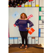 A woman in a purple shirt with her hands on her hips inside the Housingopoly game board photo booth.