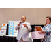 President Anthony Goodson, Jr. speaking into a microphone to the crowd with a woman holding an open box next to him.