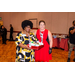 A woman holding a red gift basket with taking a picture with another woman.