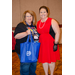 A woman holding a blue gift bag while taking a photo with another woman.