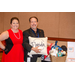 A man and a women taking a photo with the gift baskets. The man is holding a pillow that says Greetings for Florida the Sunshine State.