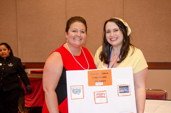 Two women with a poster board that says Pigeon Forge Tennessee Get Away.