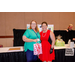 A woman holding a pink and white gift bag while taking a photo with another woman.