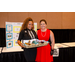 A woman holding long gift basket while posing for a photo with another individual.