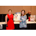 Two woman holding a gift basket between them.