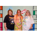 Three individuals in various decades costumes in the Housingopoly game board themed photo booth.