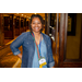 A woman smiling big for the camera while standing in a hallway.