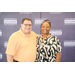 A man and a woman taking a picture in front of a Greensboro Housing Authority backdrop.