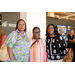 Three women smiling around a white pillar inside the International Civil Rights Center and Museum.