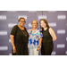 Three women smiling big in front of the Greensboro Housing Authority backdrop.