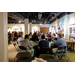 A wide shot of a room full of individuals listening as Treasure James Cox speaks.