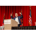 A gentleman speaking and gesturing with his hands to the crowd while standing behind a podium.