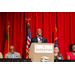 A male standing behind the podium addressing the crowd.