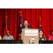 An individual standing at the podium smiling and laughing while addressing the crowd.