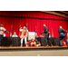 Three individuals playing a game that involves shaking your hips to get ping pong balls outside of a container that is attached to their waists.