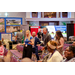 A wide shot of the crowd that is surrounded by several vendor booths.