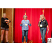 Three women standing on stage eagerly watching someone off camera.