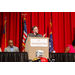 An individual gesturing and speaking with their hands behind the podium.