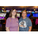 Two woman posing in front bowling alley lanes.