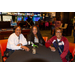 Three woman sitting around a table with a pool table behind them.